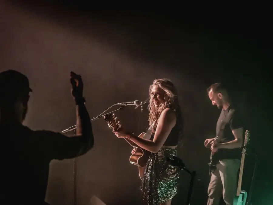 Maddison singing and playing guitar on stage with a guitarist